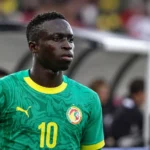 Krépin Diatta in groen Senegal-tenue langs het veld.