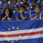 Een groep supporters van Kaapverdië zwaait met een nationale vlag in het stadion.