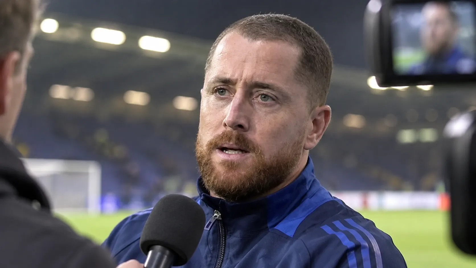 Gill Swerts tijdens een postmatchinterview in een stadionomgeving.