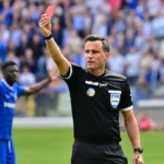 Een scheidsrechter toont een rode kaart tijdens een voetbalwedstrijd.