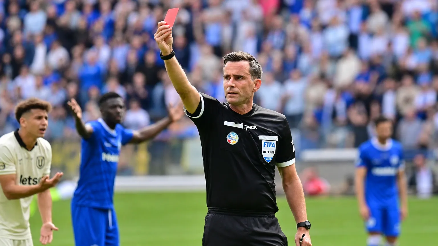 Een scheidsrechter toont een rode kaart tijdens een voetbalwedstrijd.