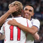 Twee Engelse spelers omhelzen elkaar op het veld na een doelpunt.