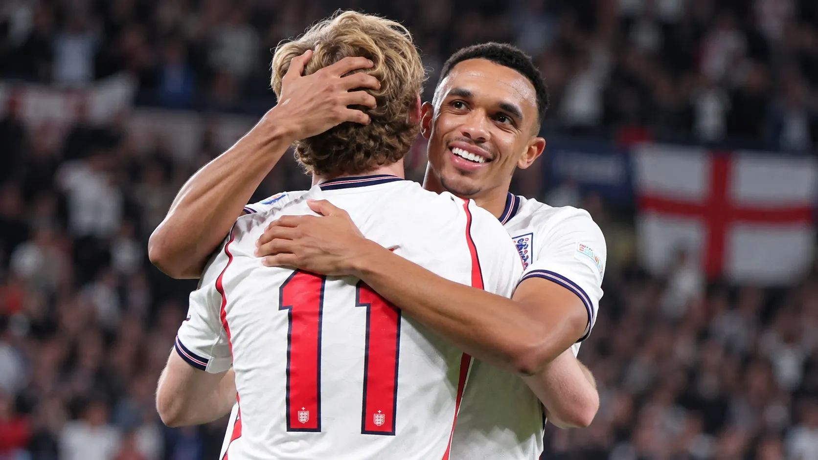 Twee Engelse spelers omhelzen elkaar op het veld na een doelpunt.