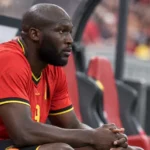 Romelu Lukaku zit in het rode tenue van België op de bank tijdens een interland.