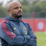 Een Bayern München-coach in trainingskleding kijkt aandachtig toe op het oefenterrein.