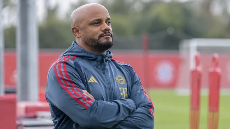 Een Bayern München-coach in trainingskleding kijkt aandachtig toe op het oefenterrein.