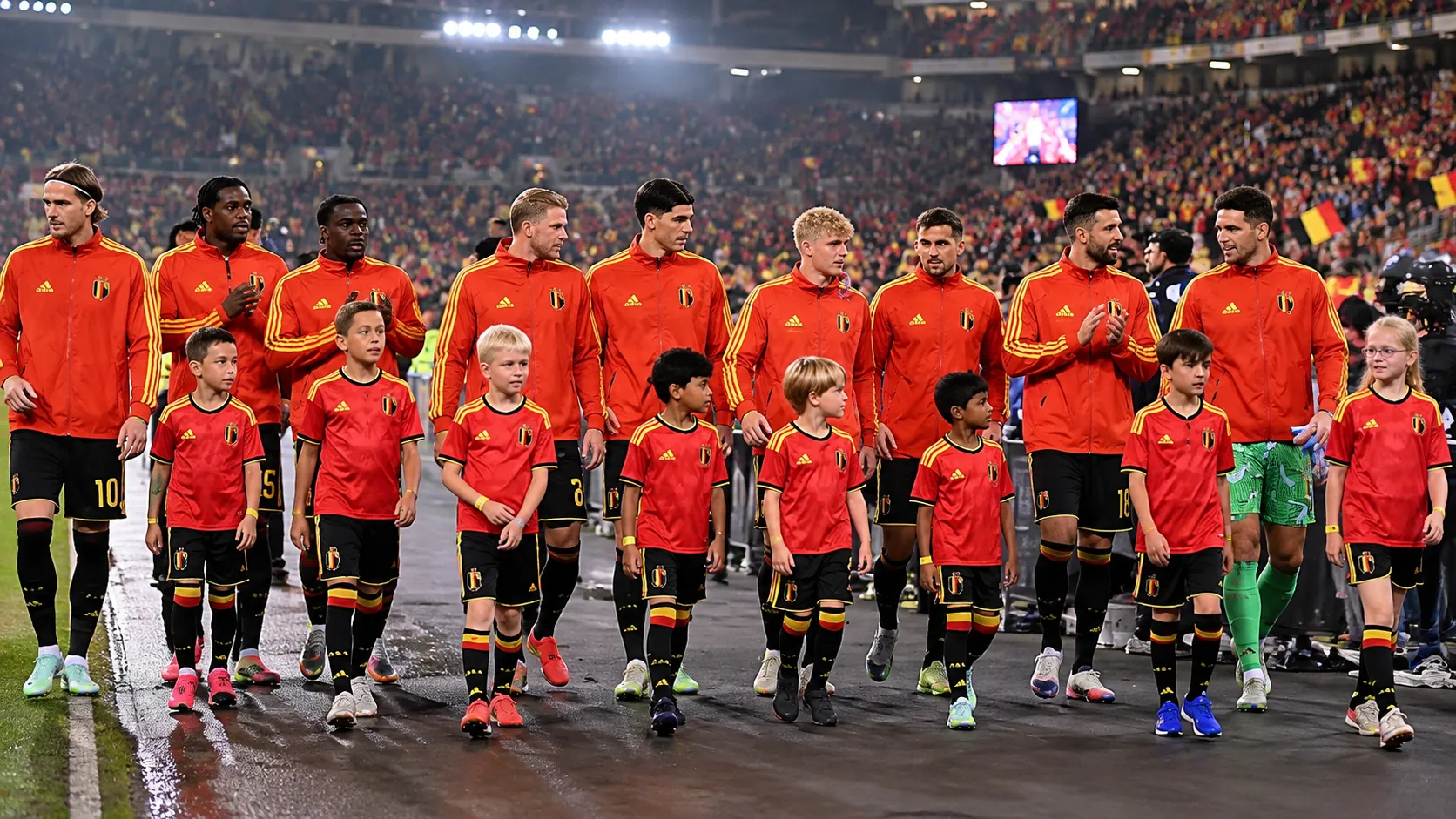 Een groep spelers in rode trainingsjassen wandelt samen op het veld na een interland.