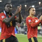Roméo Lavia applaudisseert na een wedstrijd naast een ploegmaat in een rood tenue van de Rode Duivels.