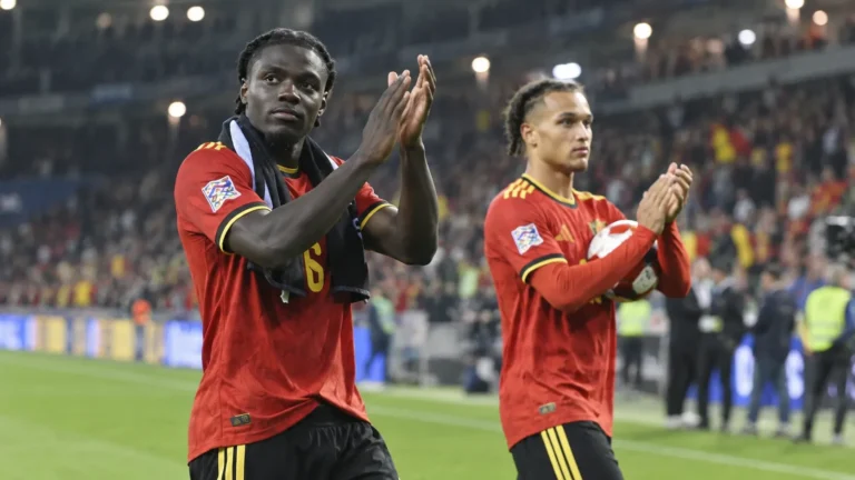 Roméo Lavia applaudisseert na een wedstrijd naast een ploegmaat in een rood tenue van de Rode Duivels.