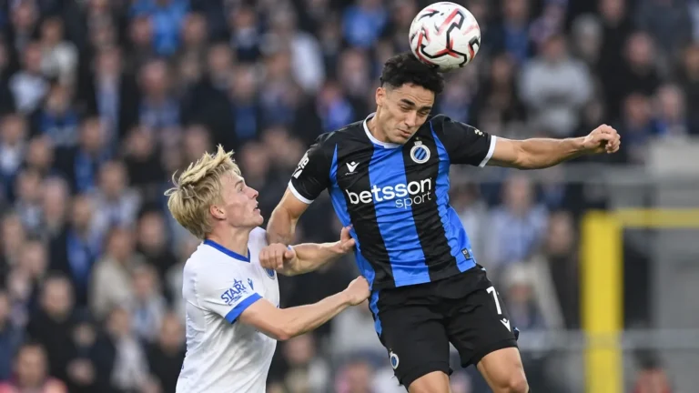 Een Club Brugge-speler kopt de bal tijdens een wedstrijdduel.