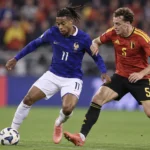 Een Belgische en een Franse voetballer in duel tijdens een interland.