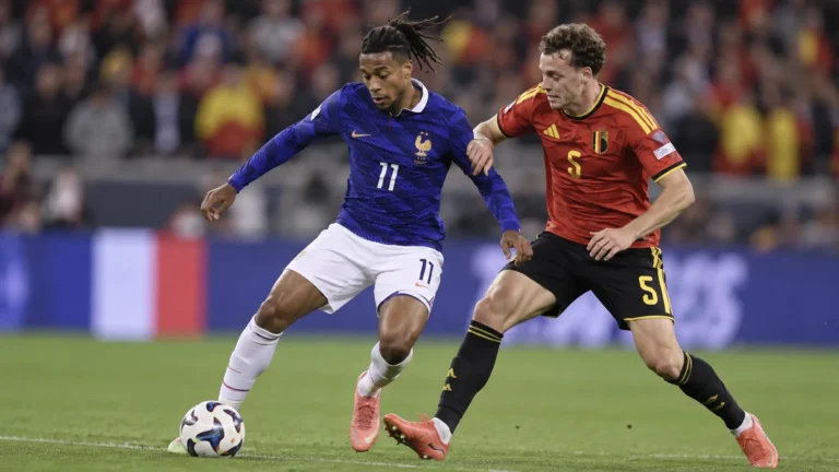 Een Belgische en een Franse voetballer in duel tijdens een interland.
