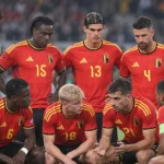 Een groep Belgische internationals in rode nationale tenues verzameld op het veld.