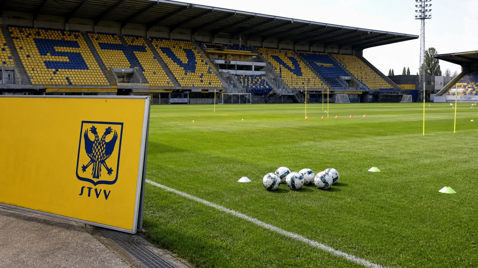 Leeg trainingsveld op Stayen met een geel STVV-trainingsbord langs de zijlijn.