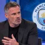 Jamie Carragher spreekt in een televisiestudio met een Manchester City-embleem op een scherm achter hem.