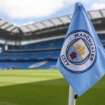 Een lichtblauwe Manchester City-hoekvlag langs het veld in een stadion.
