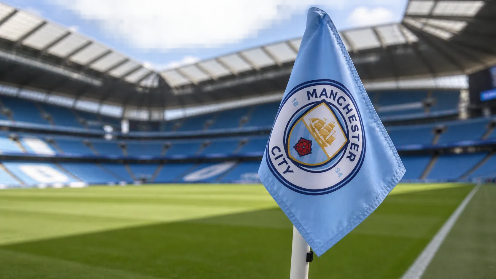 Een lichtblauwe Manchester City-hoekvlag langs het veld in een stadion.