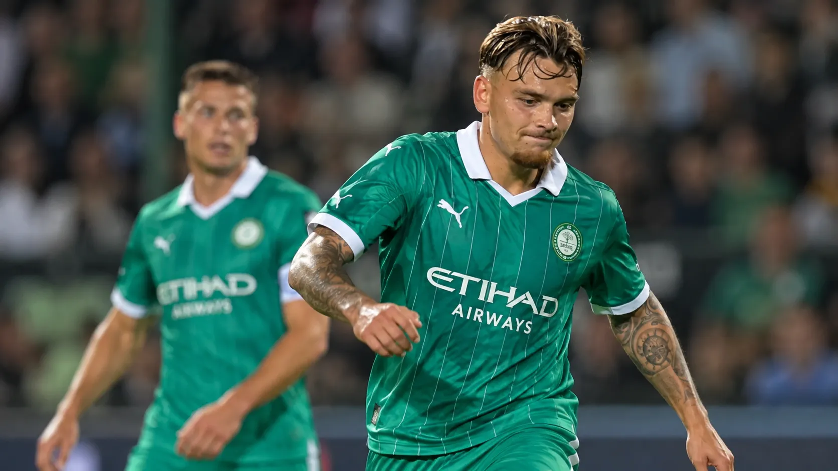 Twee voetballers in groene tenues tijdens een oefenwedstrijd.