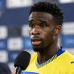 Mandela Keita tijdens een interview in zijn gele voetbalshirt.