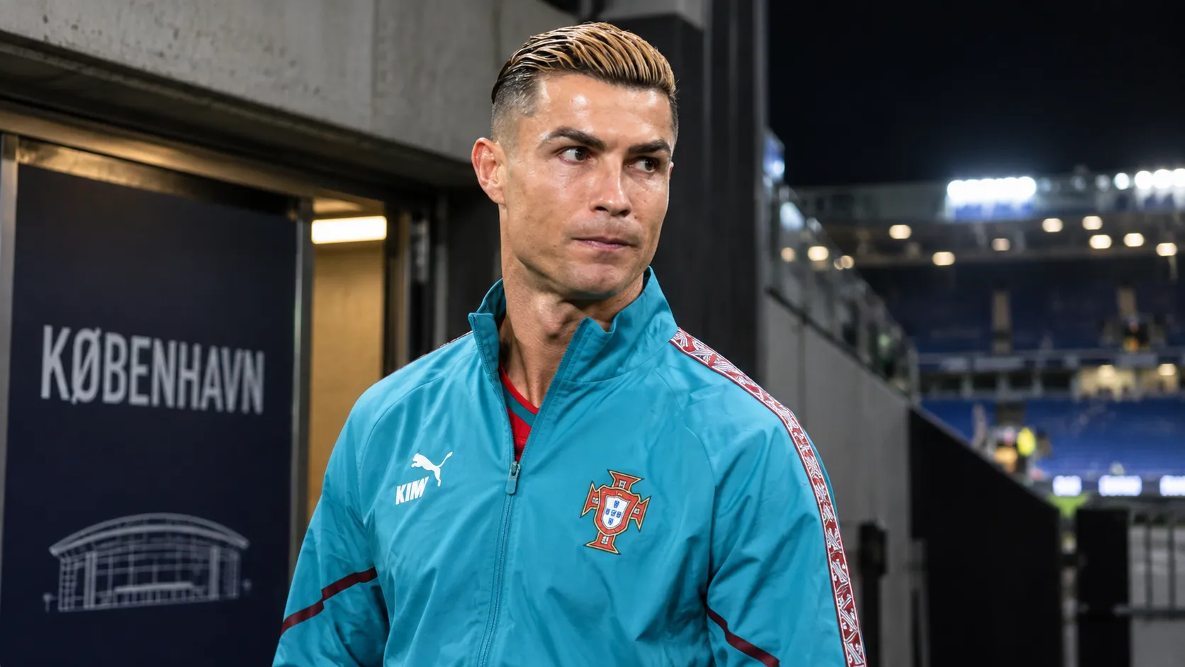 Cristiano Ronaldo in een trainingsjas van Portugal bij een stadionuitgang.