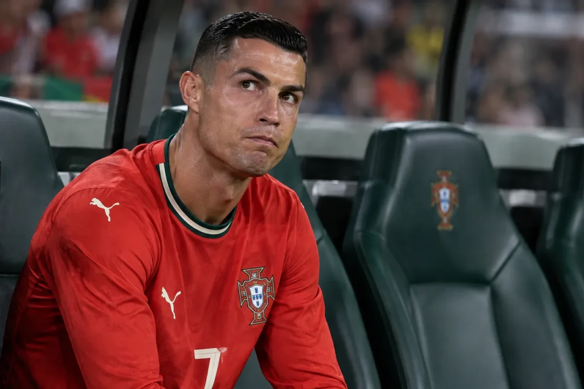 Cristiano Ronaldo zit geconcentreerd op de bank bij Portugal tijdens een Nations League-wedstrijd.