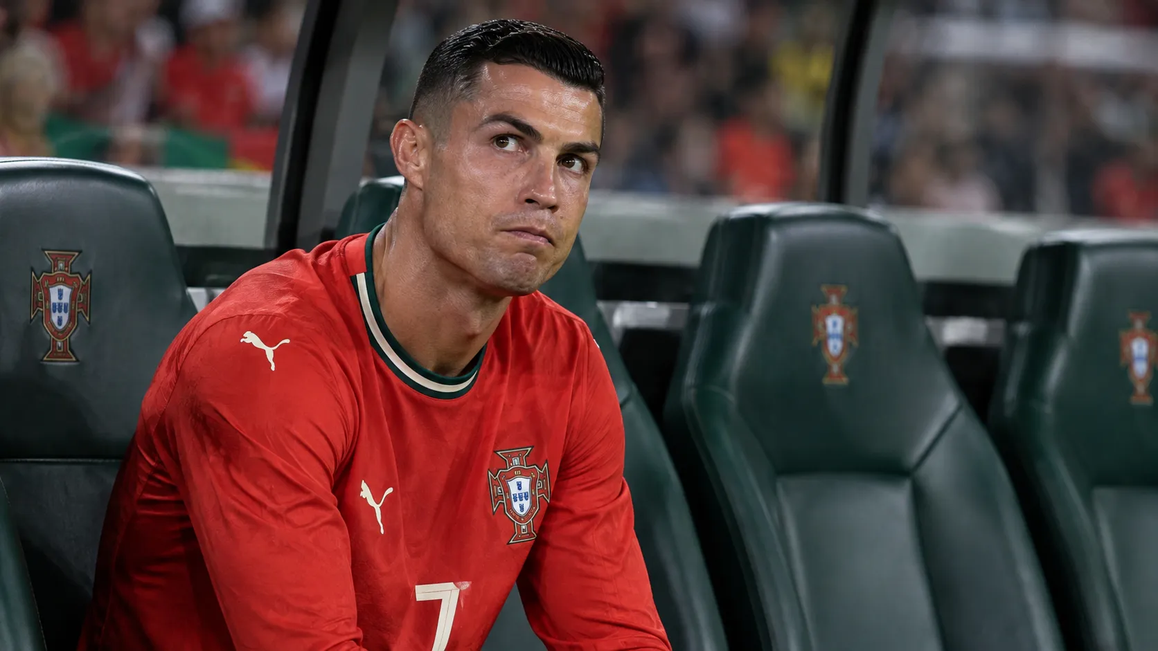 Cristiano Ronaldo zit geconcentreerd op de bank bij Portugal tijdens een Nations League-wedstrijd.