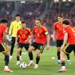 Een groep Belgische internationals in rode wedstrijdshirts warmt op in een stadion.