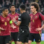 Een scheidsrechter in gesprek met Belgische internationals tijdens een interland.