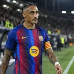 Raphinha in het shirt van FC Barcelona langs de zijlijn van een verlicht stadion.
