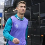 Cristiano Ronaldo in een paars trainingshesje naast een team bus.
