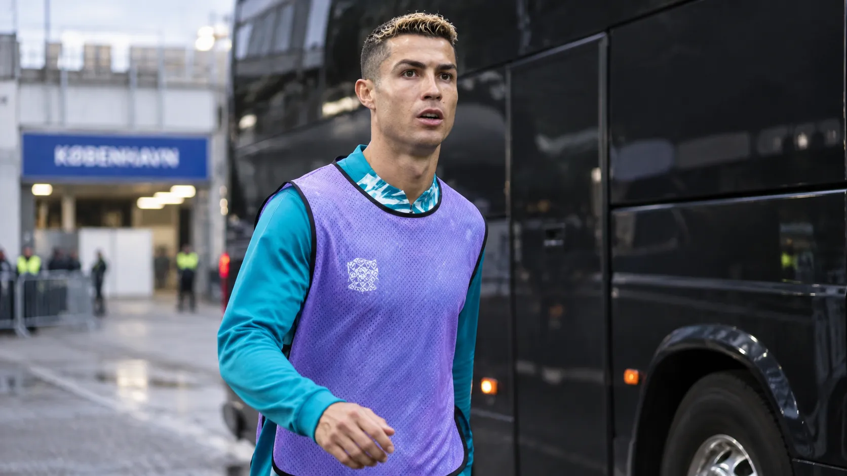 Cristiano Ronaldo in een paars trainingshesje naast een team bus.