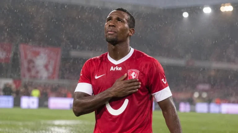 Douglas Teixeira in het rode tenue van FC Twente op een regenachtig voetbalveld.