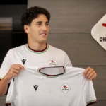 Robin Mirisola presenteert zich in een OH Leuven-tenue voor een vast clubembleem.
