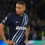 Richarlison in een donker voetbaltenue naast het veld.