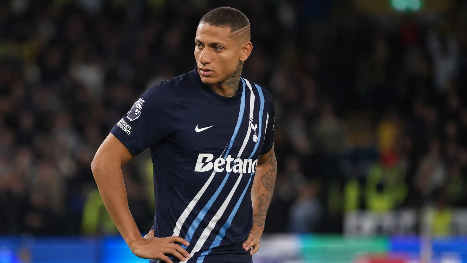 Richarlison in een donker voetbaltenue naast het veld.