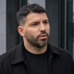 Sergio Agüero tijdens een neutraal persmoment voor een modern gebouw.