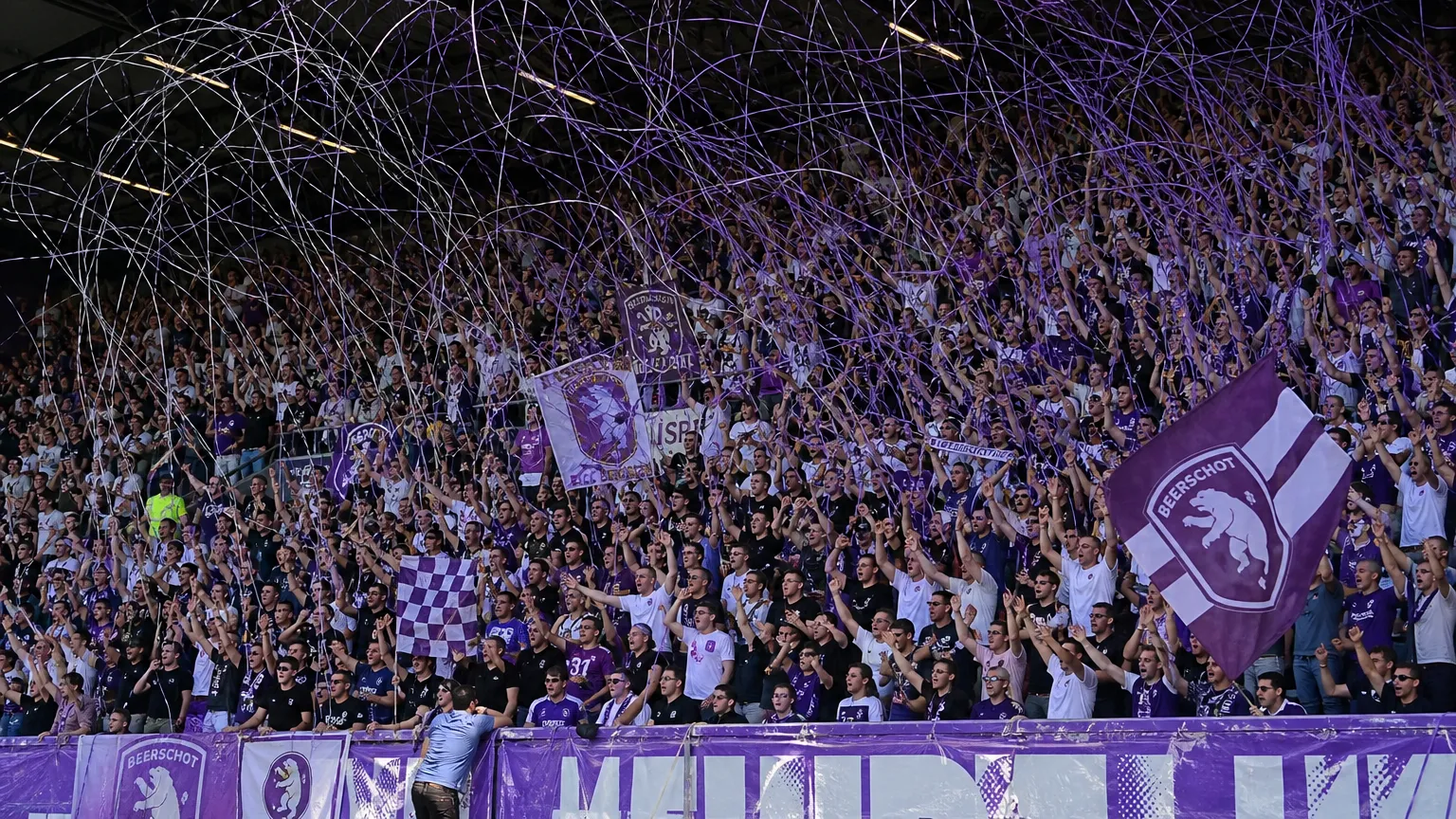 Beerschot-supporters in paars en wit vieren in een volle tribune met slierten.