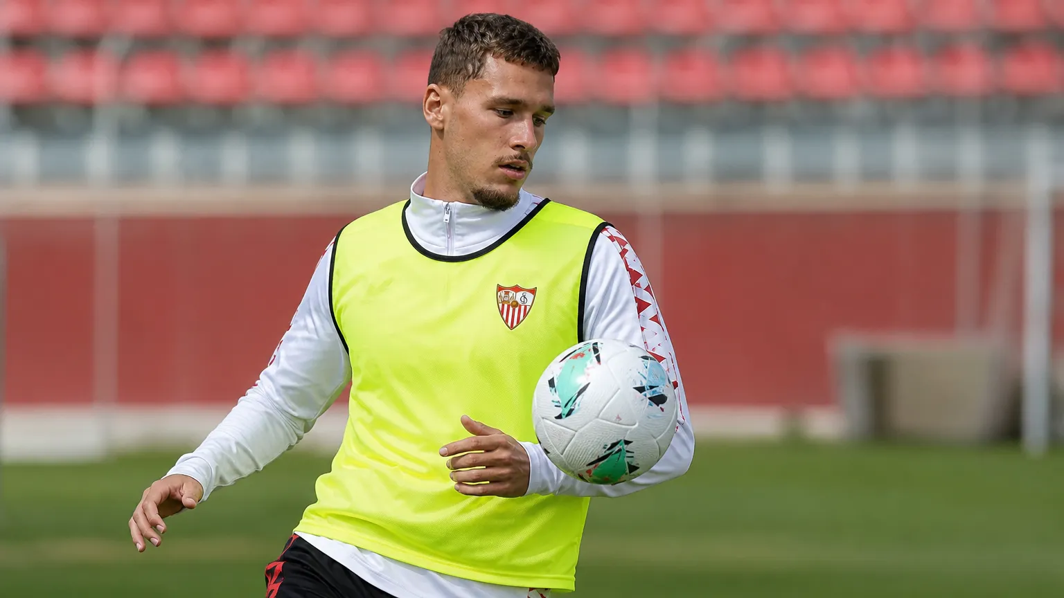 Lucas Stassin warmt op in Sevilla-trainingskleding op het trainingsveld.