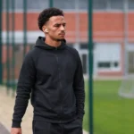 Chemsdine Talbi wandelt in neutrale sportkleding langs een trainingsveld.