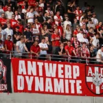 Een groep Antwerp-supporters met rood-witte spandoeken op de tribune.