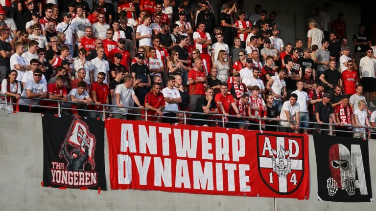 Een groep Antwerp-supporters met rood-witte spandoeken op de tribune.