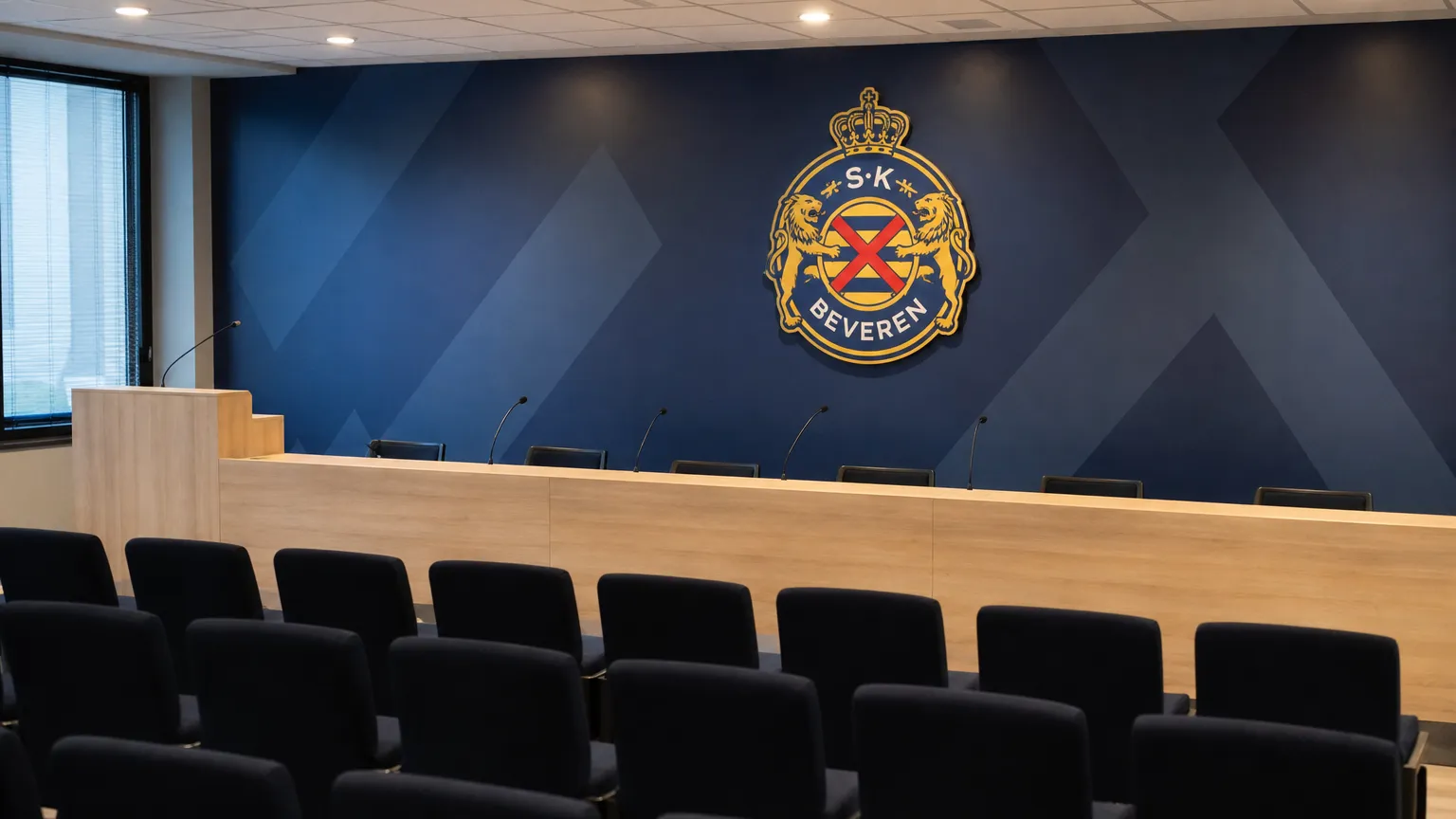 Lege communicatiehal in het clubgebouw van SK Beveren met een fysiek clubembleem aan de muur.