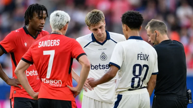 Een groep spelers van Club Brugge overlegt op het veld met een official.