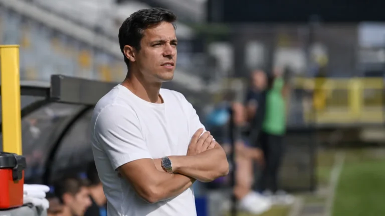 David Hubert staat geconcentreerd langs de zijlijn in een voetbalstadion.