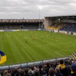 KSK Beveren in blauw en geel aan de Freethiel, met het veld, de moderne hoofdtribune en de overdekte staantribune.
