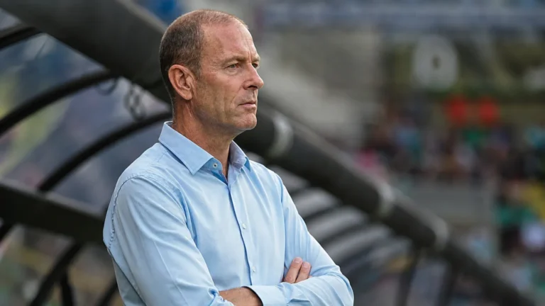 Jess Thorup kijkt geconcentreerd vanop de zijlijn in een stadion.
