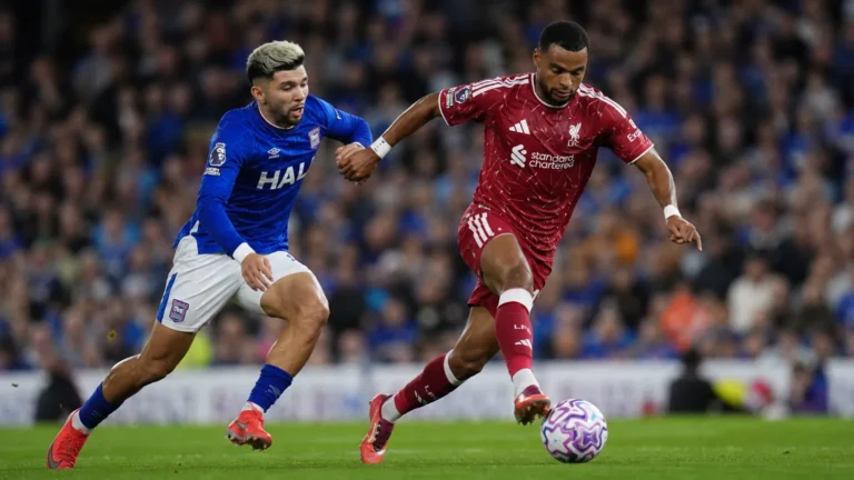 Twee spelers in rood en blauw vechten om de bal tijdens een wedstrijd.