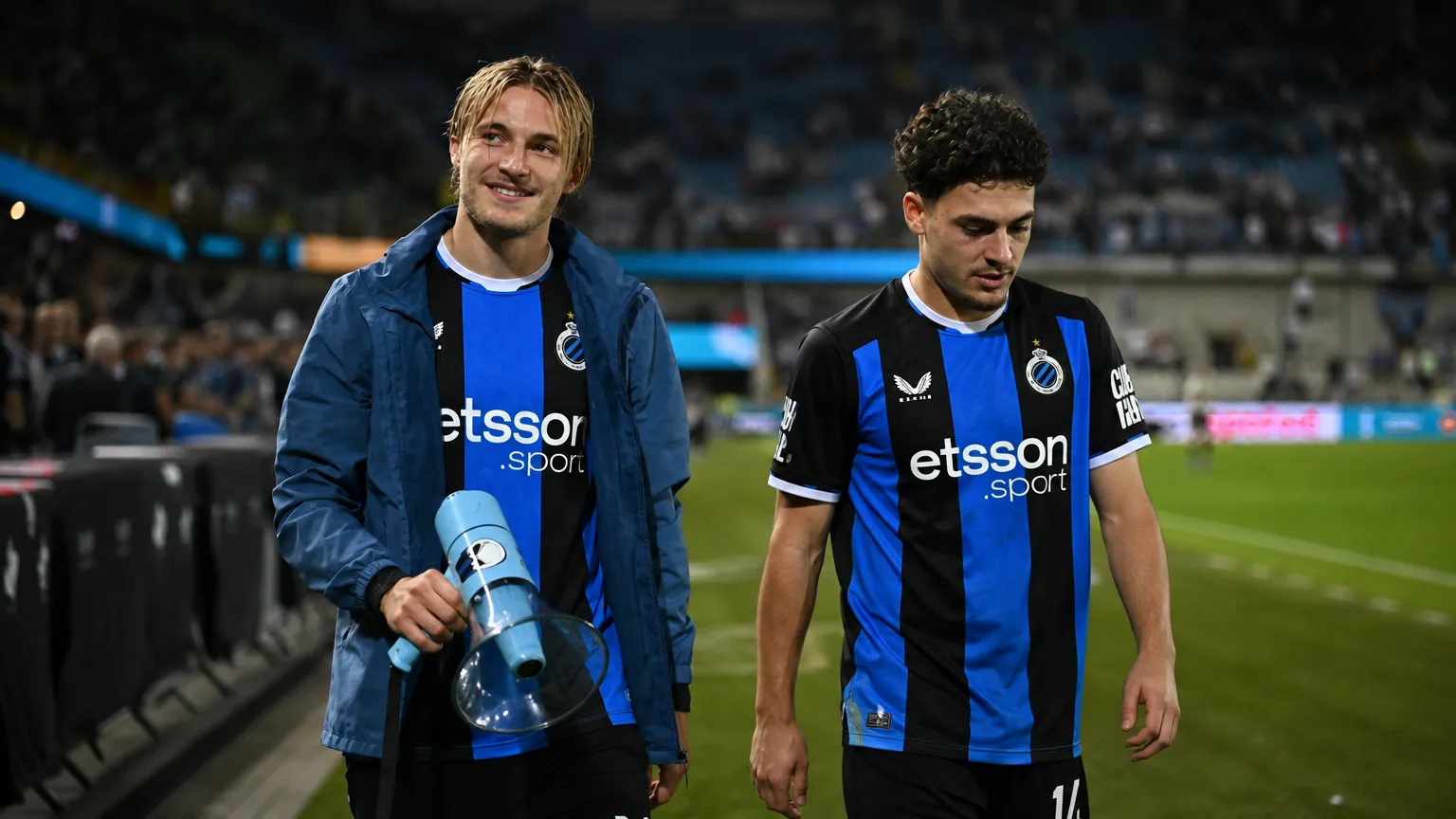 Twee Club Brugge-spelers wandelen na een wedstrijd langs de zijlijn.