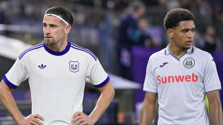 Twee voetballers in hun behouden wedstrijdkleding naast de zijlijn van een stadion.