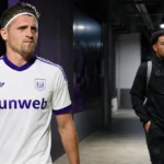 Twee voetballers wandelen door de overdekte ingang van een clubcomplex.